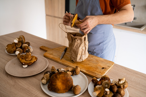 Unrecognizable chef, cleaning boletus mushroom with brush in the kitchen