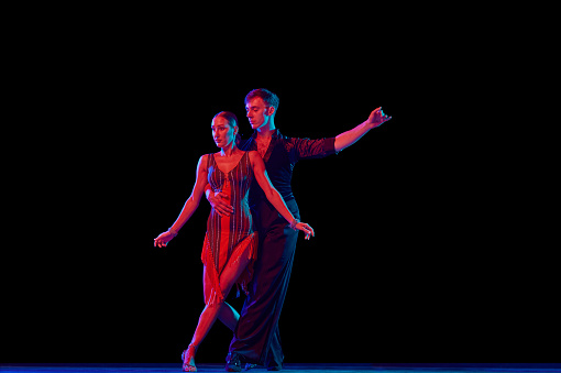 Love. Poetry in motion. Emotional dancers dancing ballroom dance isolated on dark background. Concept of art, dance, beauty, music, style. Copy space for ad. International Dance Day
