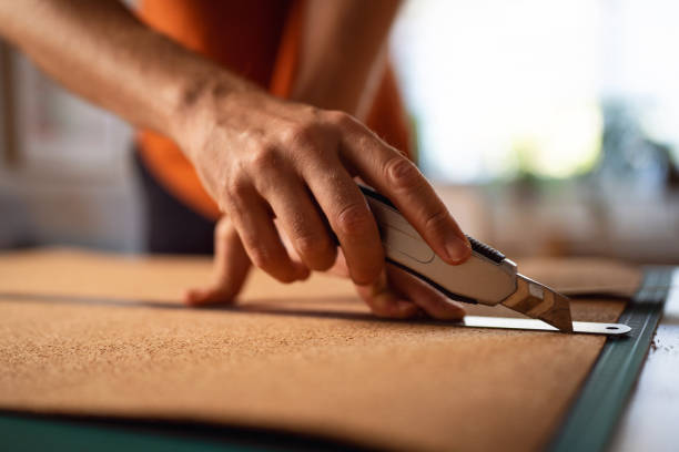 Unrecognizable male architect cutting the cork with scalpel while making architectural model