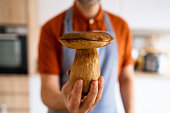 Portrait of chef, holding big boletus mushroom with knife