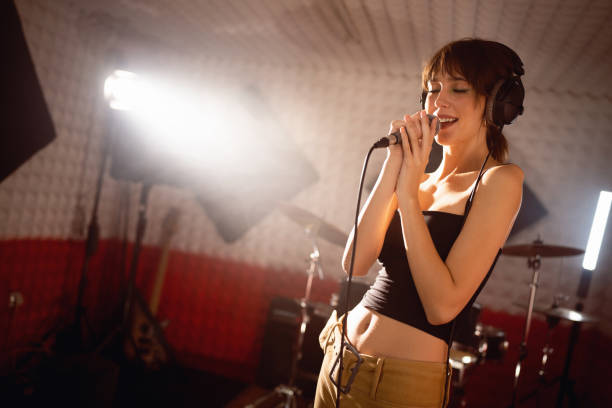 istock Young woman singing, while recording song at the music studio 1432888590