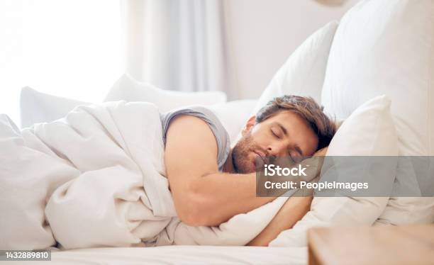 Home Bedroom And Sleeping Man In The Morning Lying His Head On The Pillow In Apartment Space Tired Fatigue And Relax Male Taking Time Off On The Weekend In Bed Of Airbnb Or Hotel Accommodation Stock Photo - Download Image Now