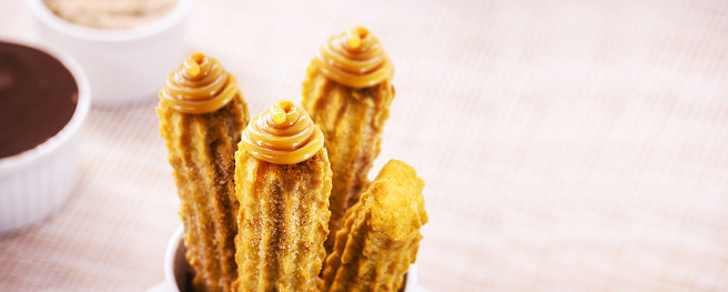Churros, typical fried sweet from Brazil, Mexico and Spain, made from wheat flour and water, sprinkled with a layer of sugar or cinnamon, filled with dulce de leche, copy space