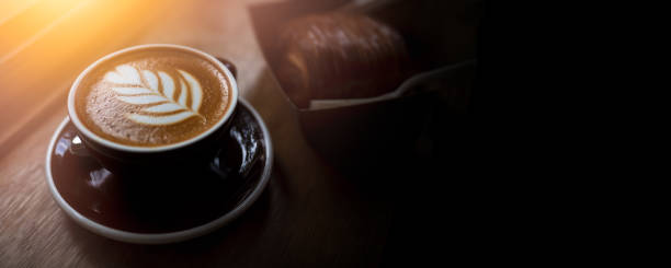 Coffe Latte Art and croissant on sunray sunrise in morning banner page cover include empty space for text graphic advertise stock photo