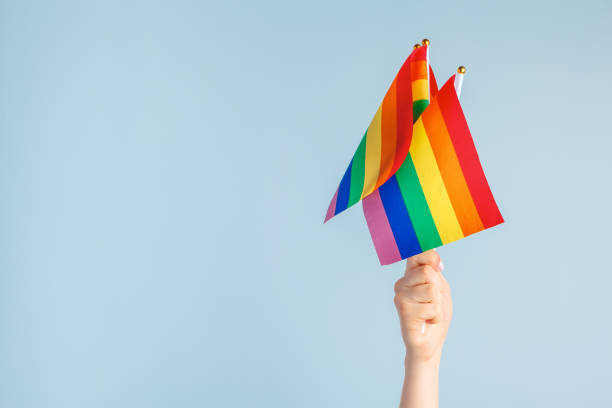 istock Gay flags in women's hand on grey background 1432893819
