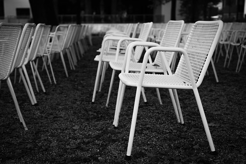 Rows of white metal garden chairs in front of an outdoor stage. Series, 5of6