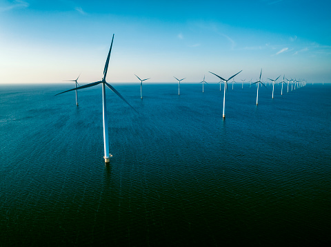 Wind turbines producing sustainable renewable energy in an offshore wind park in Flevoland, The Netherlands. Drone point of view.