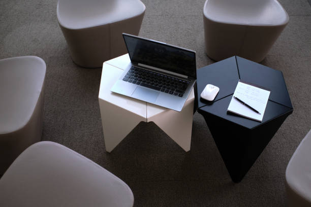 istock Open notebook with mouse and note pad on small white and black tables in the modern office environment 1432898071