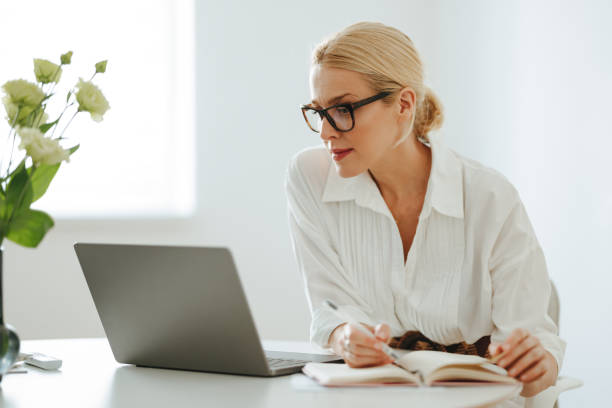 piękna kobieta biznesu korzystająca z laptopa w pracy - biała kobieta czyta w okularach zdjęcia i obrazy z banku zdjęć