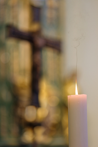 Selective focus on votive lit candle with bright soft glow and blurred background of interior of St. Marys Cathedral in Killarney, Kerry, Ireland