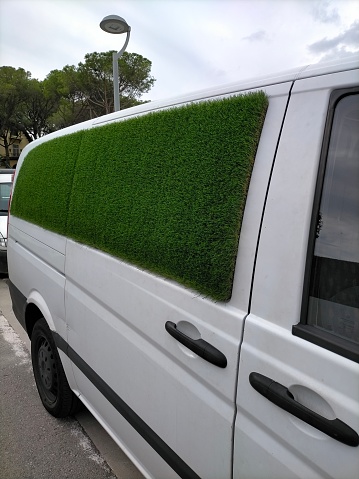 Biomimetic van, integration of nature. White car with grass lined side windows.