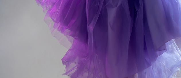Сlose-up of violet blue chiffon dress curiously bending under the hands of a girl in the studio. Lavender fabric tulle texture. color of the year 2022 very peri.