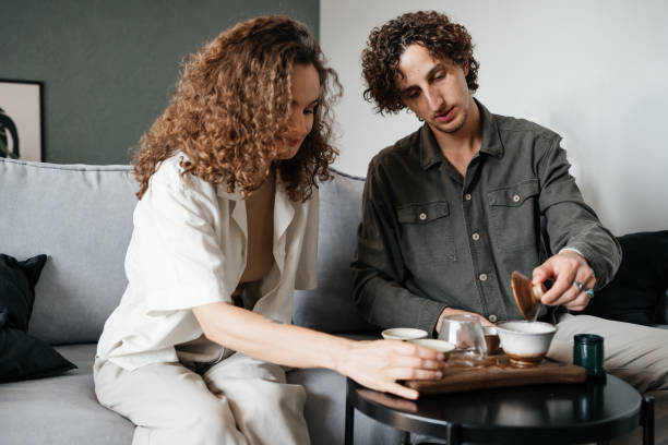 istock Couple drinking tea sitting on sofa in room. 1432901919