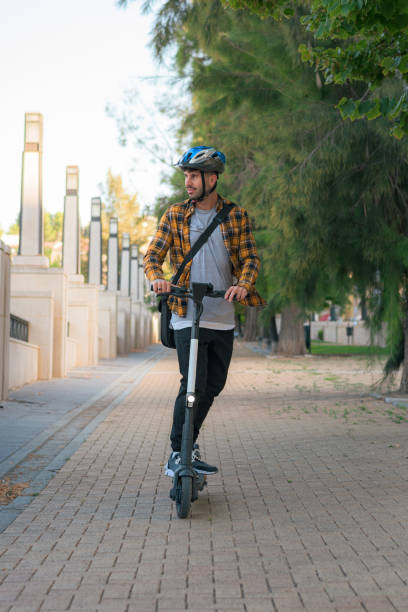 istock Young man riding an electric scooter through a park 1432901961