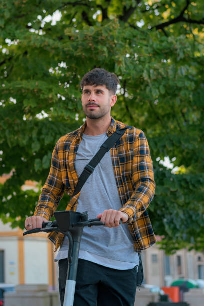istock Young man riding an electric scooter through a park 1432901989