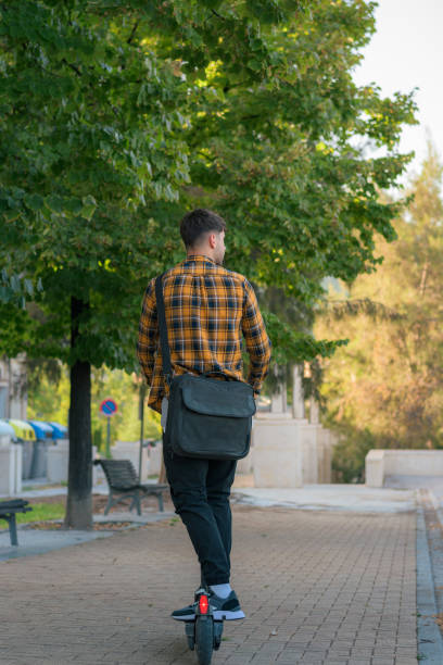 istock Young man riding an electric scooter through a park 1432901995