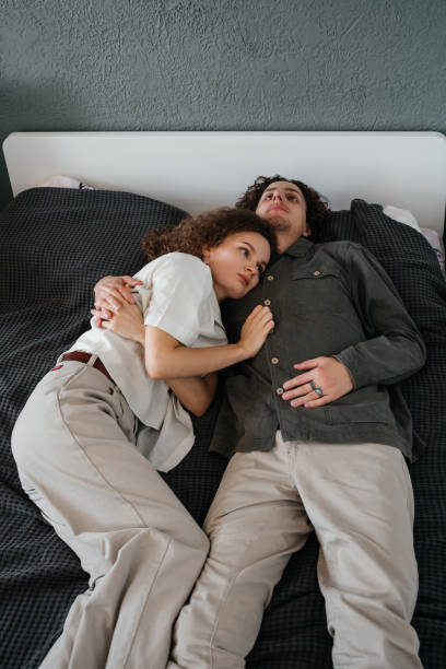 istock Young couple lying in bed hugging but worried. 1432902042