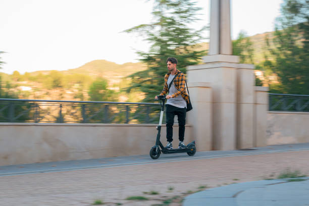 istock Man riding an electric scooter through a park at high speed 1432902557