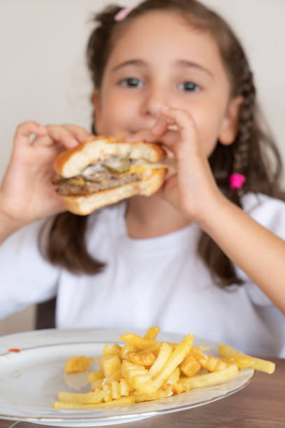 istock Little girl eating a big burger 1432903121