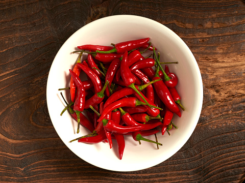 Red hot chili pepper with bowl on old wooden background.