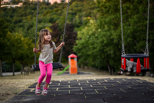 Children, free time, vacations. Smiling girl playing on the swing