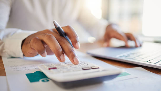finance, accounting and fintech, a man on a computer and calculator working out his business budget strategy. businessman at his office desk, laptop, money management and financial investment online. - investering stockfoto's en -beelden
