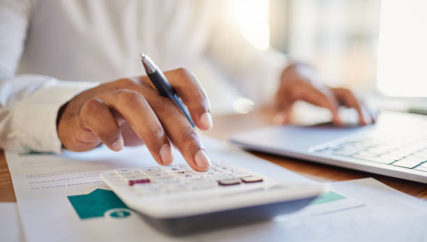 Finance, accounting and fintech, a man on a computer and calculator working out his business budget strategy. Businessman at his office desk, laptop, money management and financial investment online. Finance, accounting and fintech, a man on a computer and calculator working out his business budget strategy. Businessman at his office desk, laptop, money management and financial investment online. instrument for counting stock pictures, royalty-free photos & images