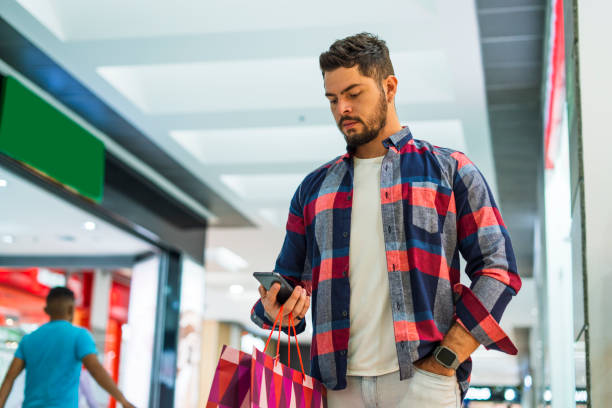 istock young man is in a shopping mall while holding his cell phone in his hand 1432910184