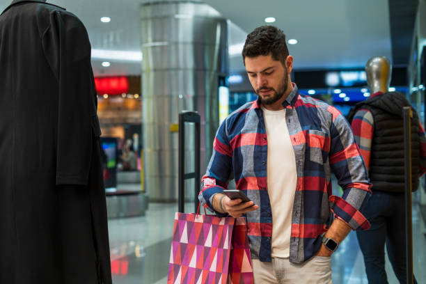 istock young man is in a shopping mall while holding his cell phone in his hand 1432910761
