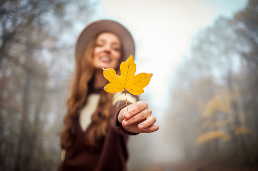 Portrait of beautiful young woman holding yellow leaf
