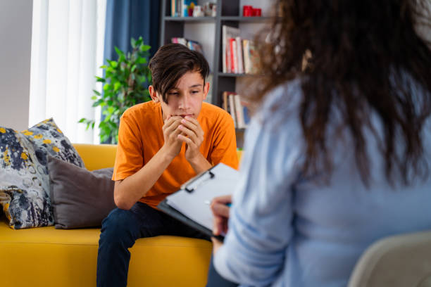 female psychologist counseling teenage boy in office - terapia alternativa imagens e fotografias de stock