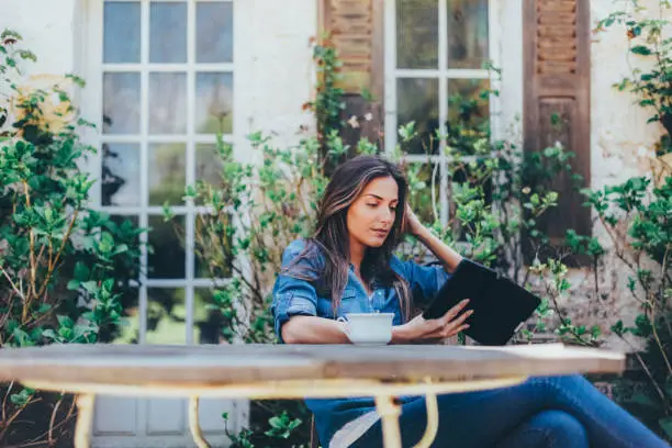 Woman drinking tea and reading a book in the garden