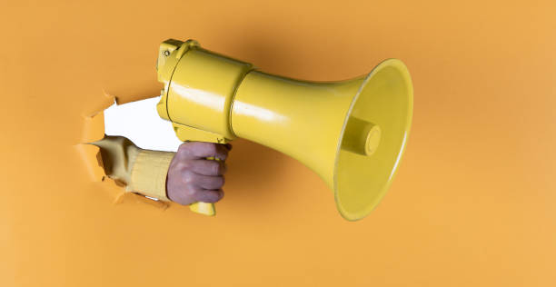istock megaphone in hand in yellow paper hole 1432919752