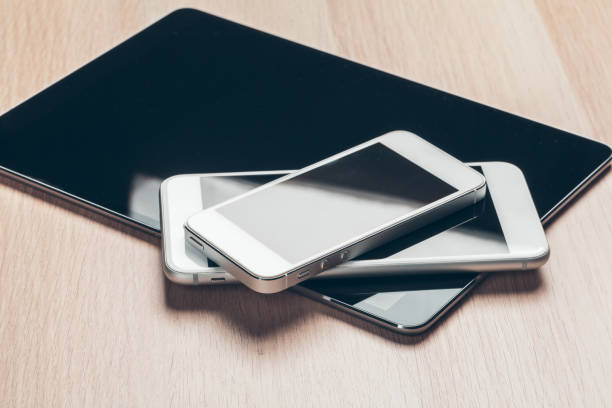 Digital tablet and mobile phone. Electronic devices on wooden table, close up.