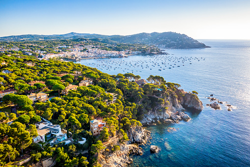 Aerial view of Costa Brava coast with camí de ronda path early in the morning with Calella de Palafrugell and boats in the background