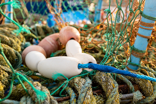 Shallow focus of fishing net floats seen in a large lobster pot located on a beach on the Suffolk, UK coast.