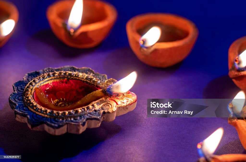 Closeup of Diwali Diya or Oil Lamp Flame with Selective Focus Isolated on Blue Background, Happy Deepavali or Diwali Conceptual, Festival of Lights Closeup of Diwali Diya or Oil Lamp Flame with Selective Focus Isolated on Blue Background, Happy Deepavali or Diwali Conceptual, Festival of Light. Diwali Stock Photo