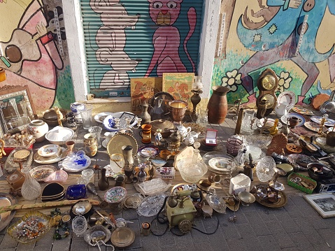 Milan, Italy - July 2, 2022: A collection of random and assorted used items at a flea market vendor's table in the Canal District in Milan