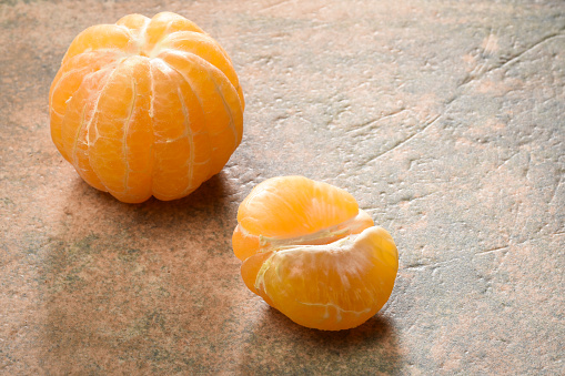 Peeled tangerine mandarin slices on the granite stone background with copy space