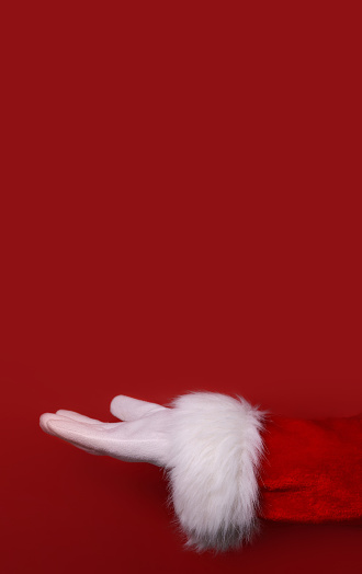 Santa Claus hand presenting your text, product, advertisement on a red background.Mockup. Copy space.