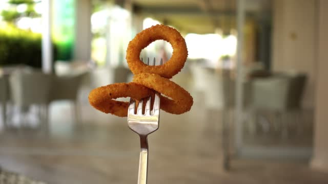 Squid rings on the fork. Rings in breading, rotate against the background of the hotel lobby or business center.