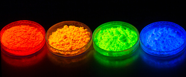 Fluorescent organic materials powder of red, yellow, green color for production OLED displays in UV light. Closeup.