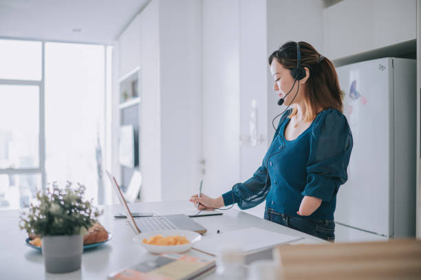istock Chinese Woman with disability deformed arm work from home video call at kitchen counter business meeting virtual event 1432937367