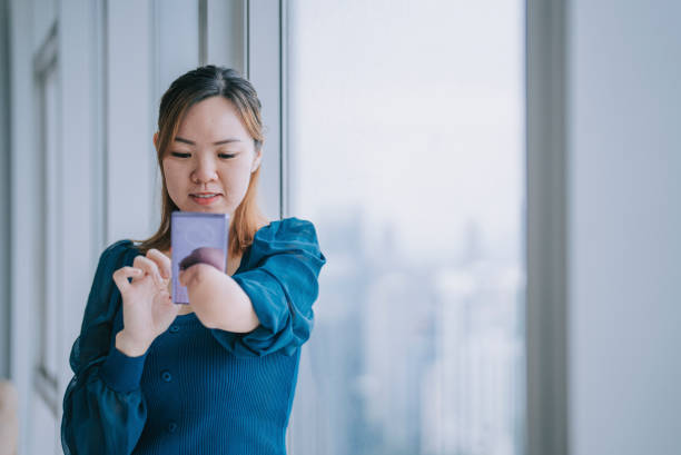 mujer asiática china con el brazo deformado de la discapacidad revisando los mensajes de texto en casa apoyada en la ventana - mobile phone text telephone message fotografías e imágenes de stock