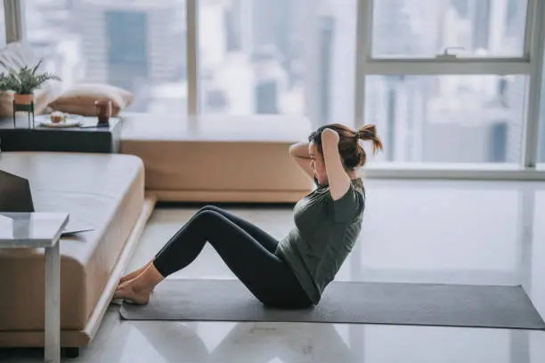 Photo of Chinese woman with disability deformed arm sit up home workout watching online class guidance with laptop