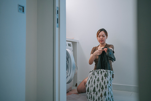 Asian chinese woman with disability deformed arm doing laundry at home