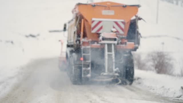 Blurred footage of services snow plow truck clear covered roads after heavy winter storm snow fall, slow motion