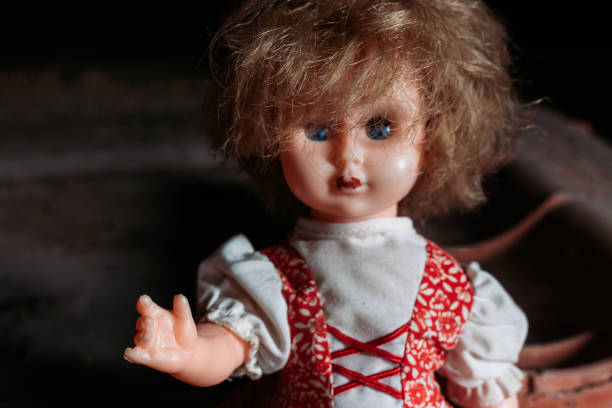 istock Old doll sitting on dirty ground. Scary look, Halloween concept 1432941253