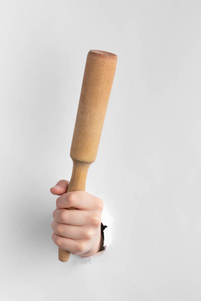 istock child hand through hole in white paper with torn edges holding a wooden rolling pin. kitchen tool for cooking above a paper background 1432943936