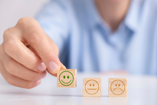 Customer satisfaction survey concept, Close-up shot of hands holding smiley face icon on wooden cube, service rating, leadership concept.